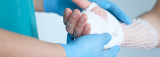 Arzt hält Hand, die mit Netzschlauchverband verbunden ist
