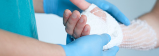 Médecin tenant la main sur laquelle on pose une bande avec filet tubulaire