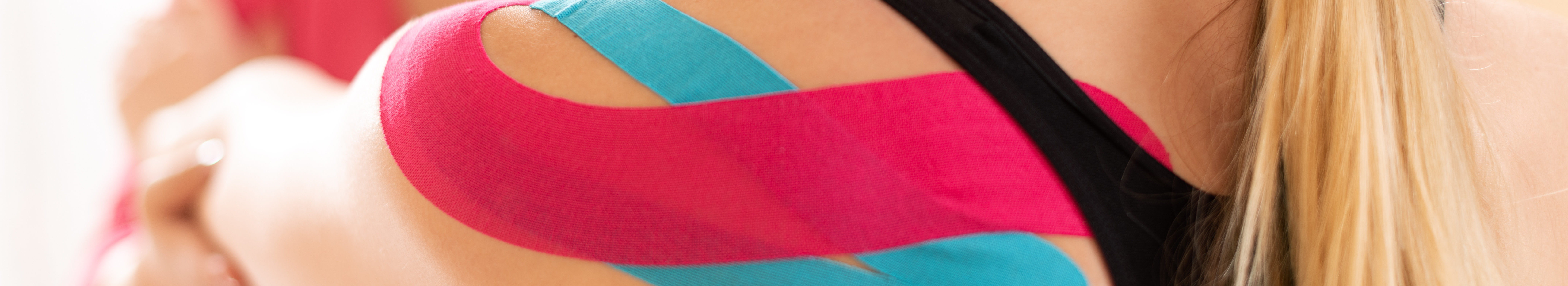 Woman having kinesiology tape applied to shoulder