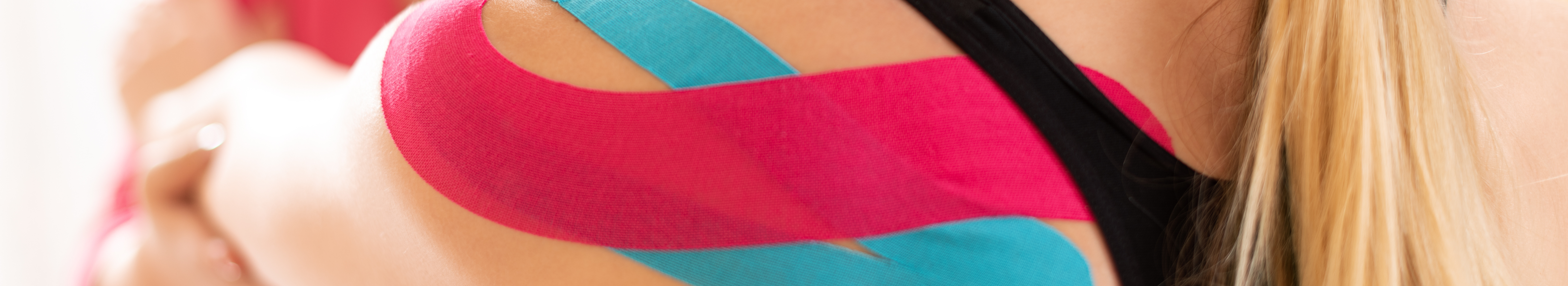 Woman having kinesiology tape applied to shoulder