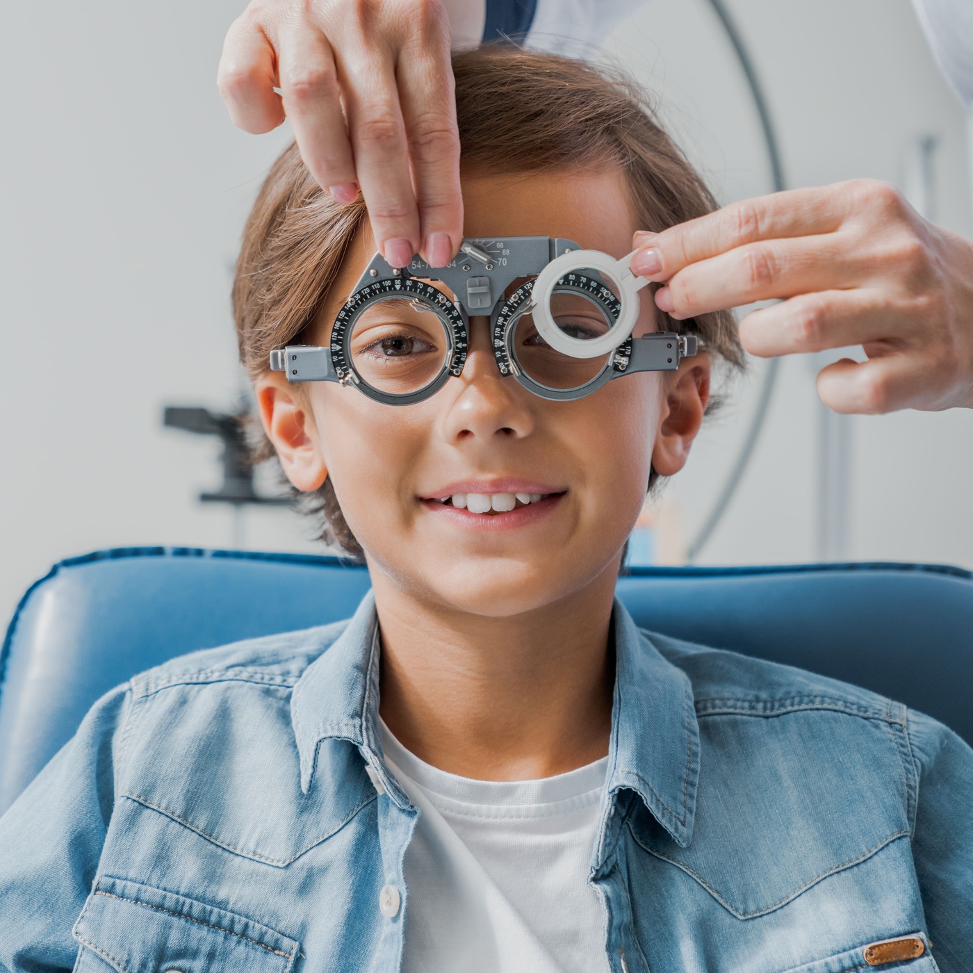 Niño pequeño sonriendo mientras le ponen unas gafas de prueba de diagnóstico ocular.