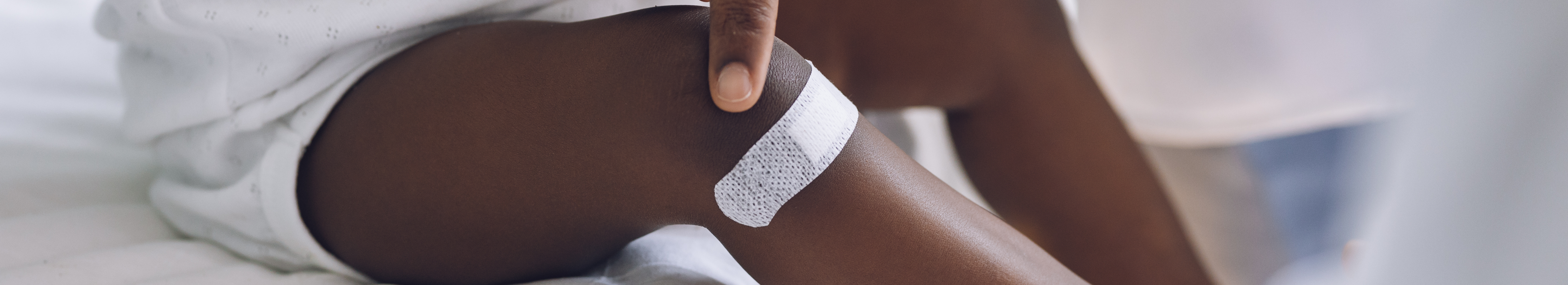 Infant with pigmentation, with white wound plaster on leg