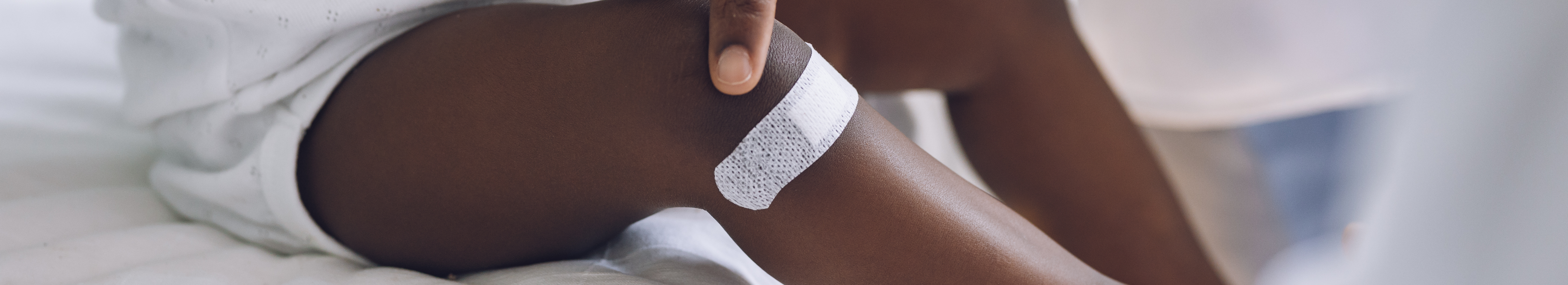 Petit enfant avec pigmentation portant un pansement adhésif sur la jambe