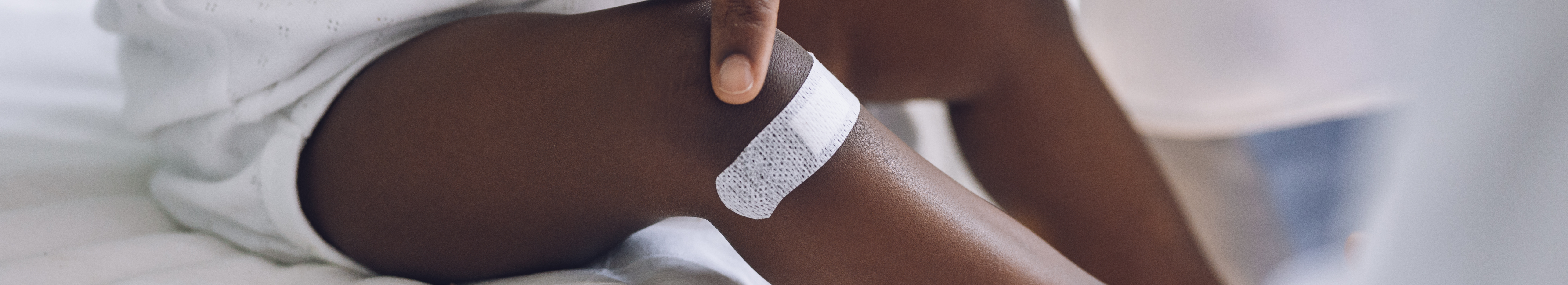 Petit enfant avec pigmentation portant un pansement adhésif sur la jambe