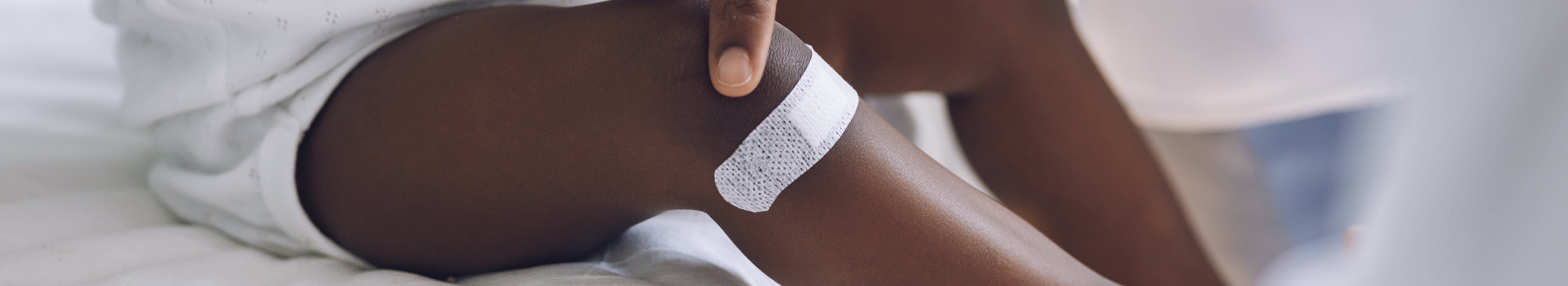 Petit enfant avec pigmentation portant un pansement adhésif sur la jambe