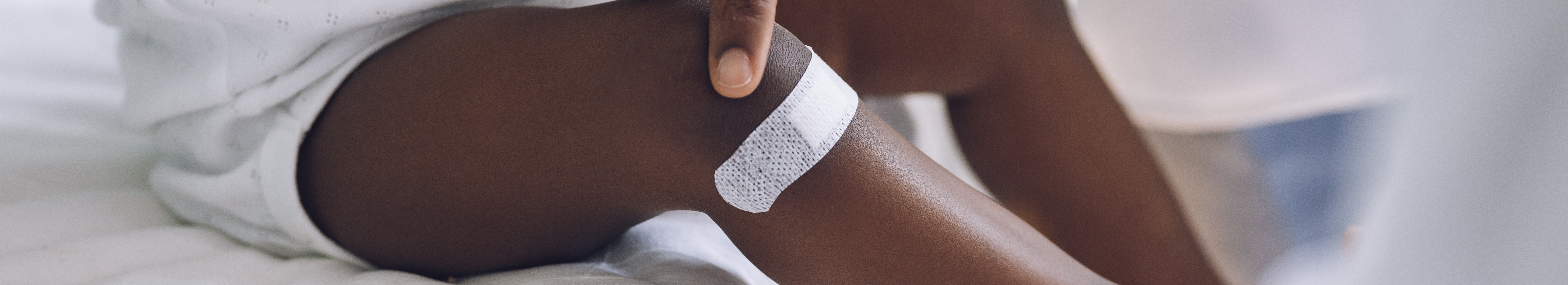 Petit enfant avec pigmentation portant un pansement adhésif sur la jambe