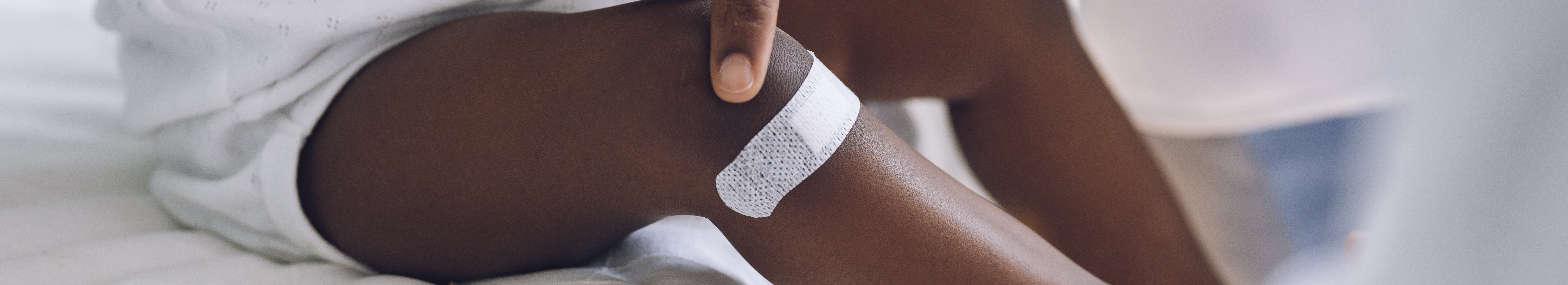 Petit enfant avec pigmentation portant un pansement adhésif sur la jambe