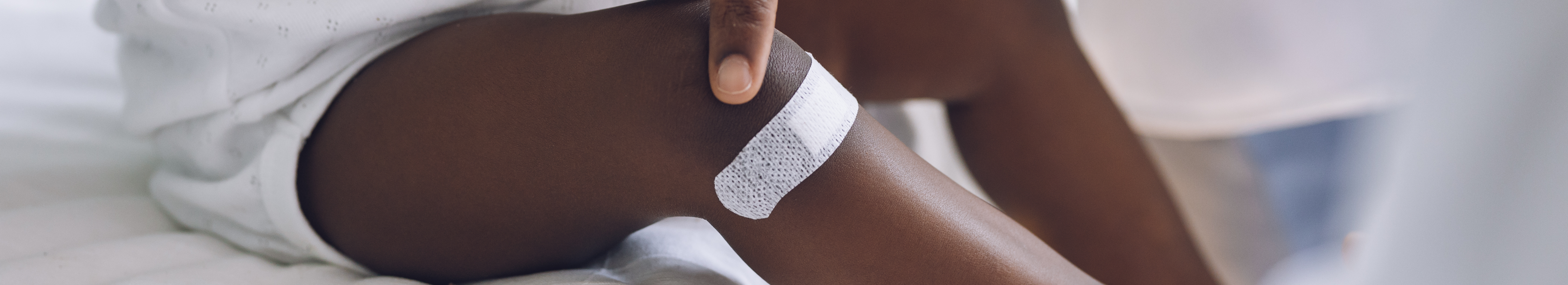 Infant with pigmentation, with white wound plaster on leg