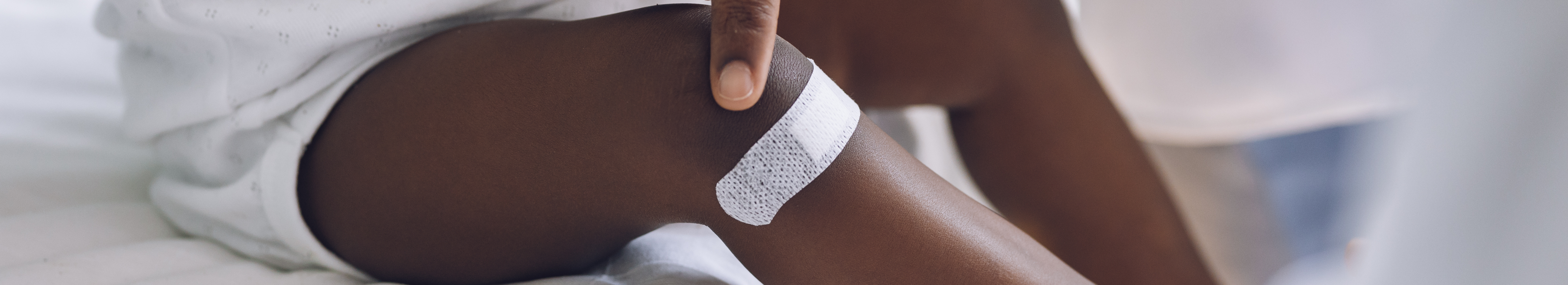 Infant with pigmentation, with white wound plaster on leg