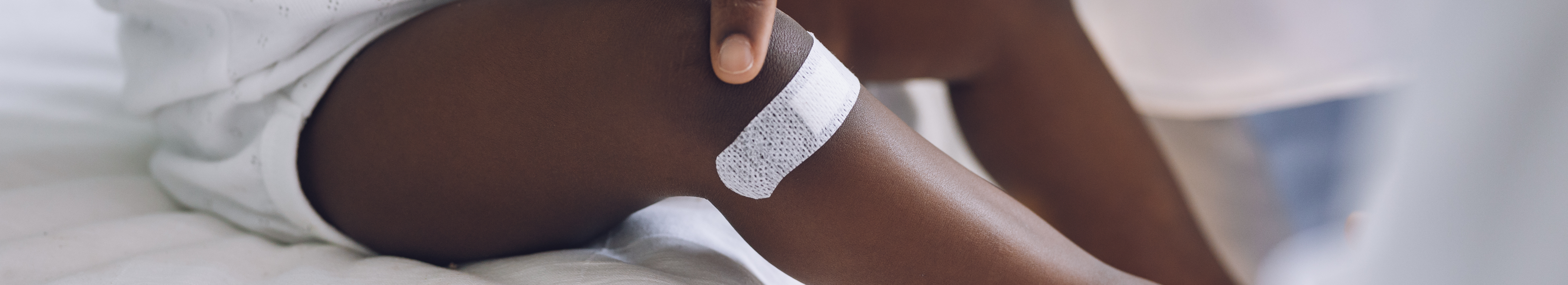 Petit enfant avec pigmentation portant un pansement adhésif sur la jambe