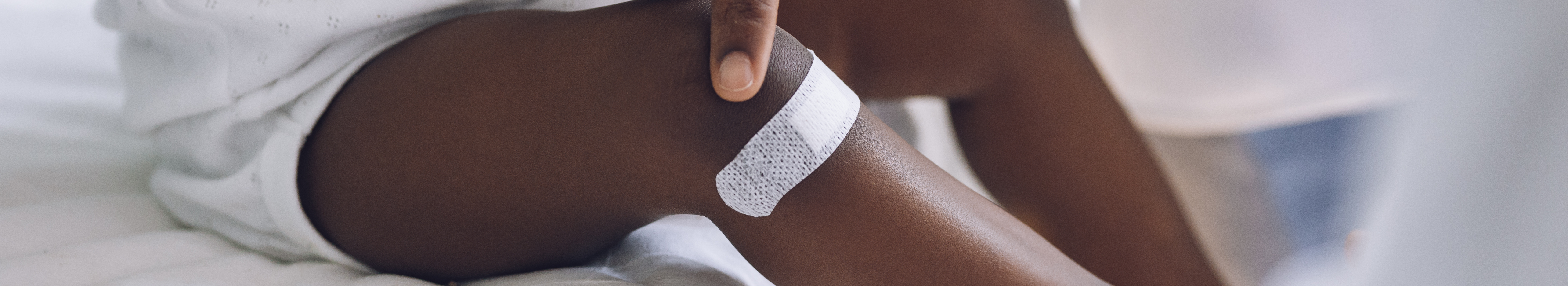 Infant with pigmentation, with white wound plaster on leg