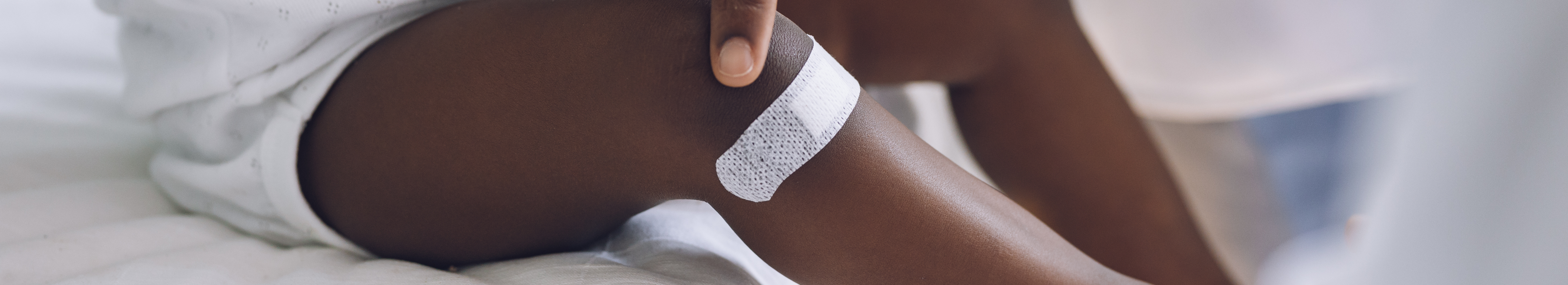 Infant with pigmentation, with white wound plaster on leg