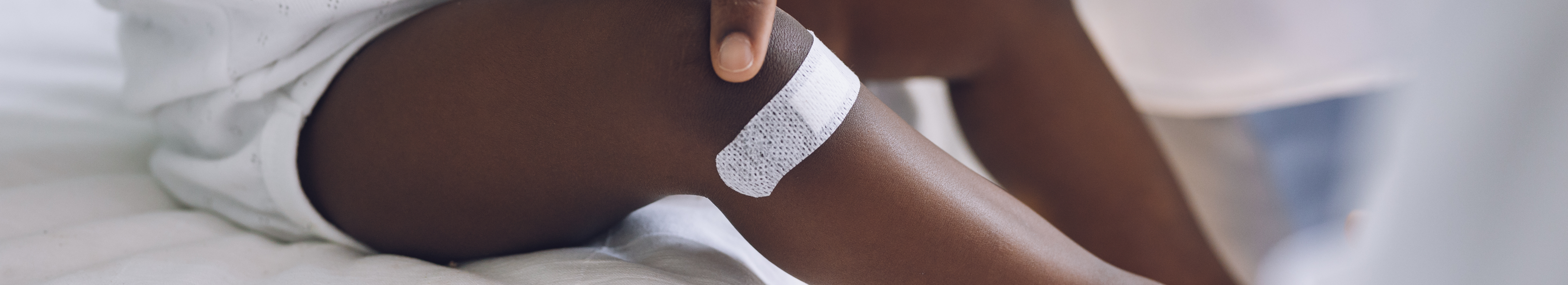 Petit enfant avec pigmentation portant un pansement adhésif sur la jambe