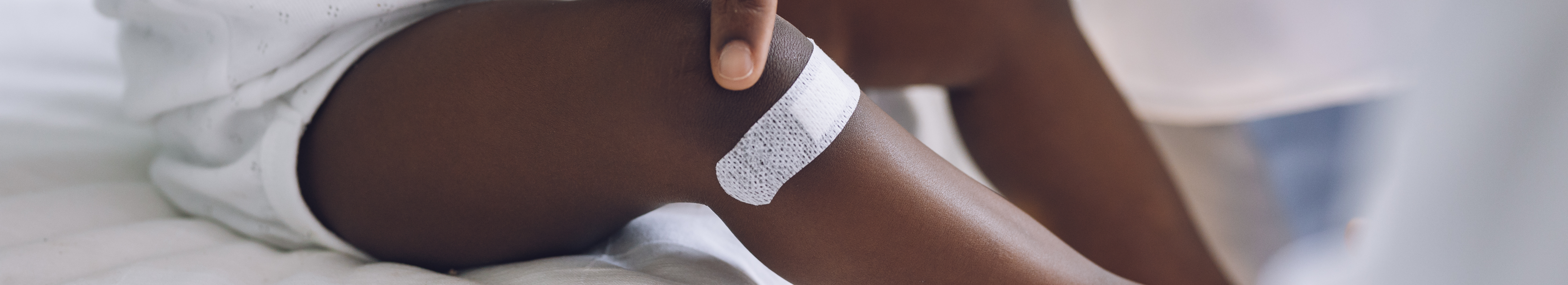 Infant with pigmentation, with white wound plaster on leg