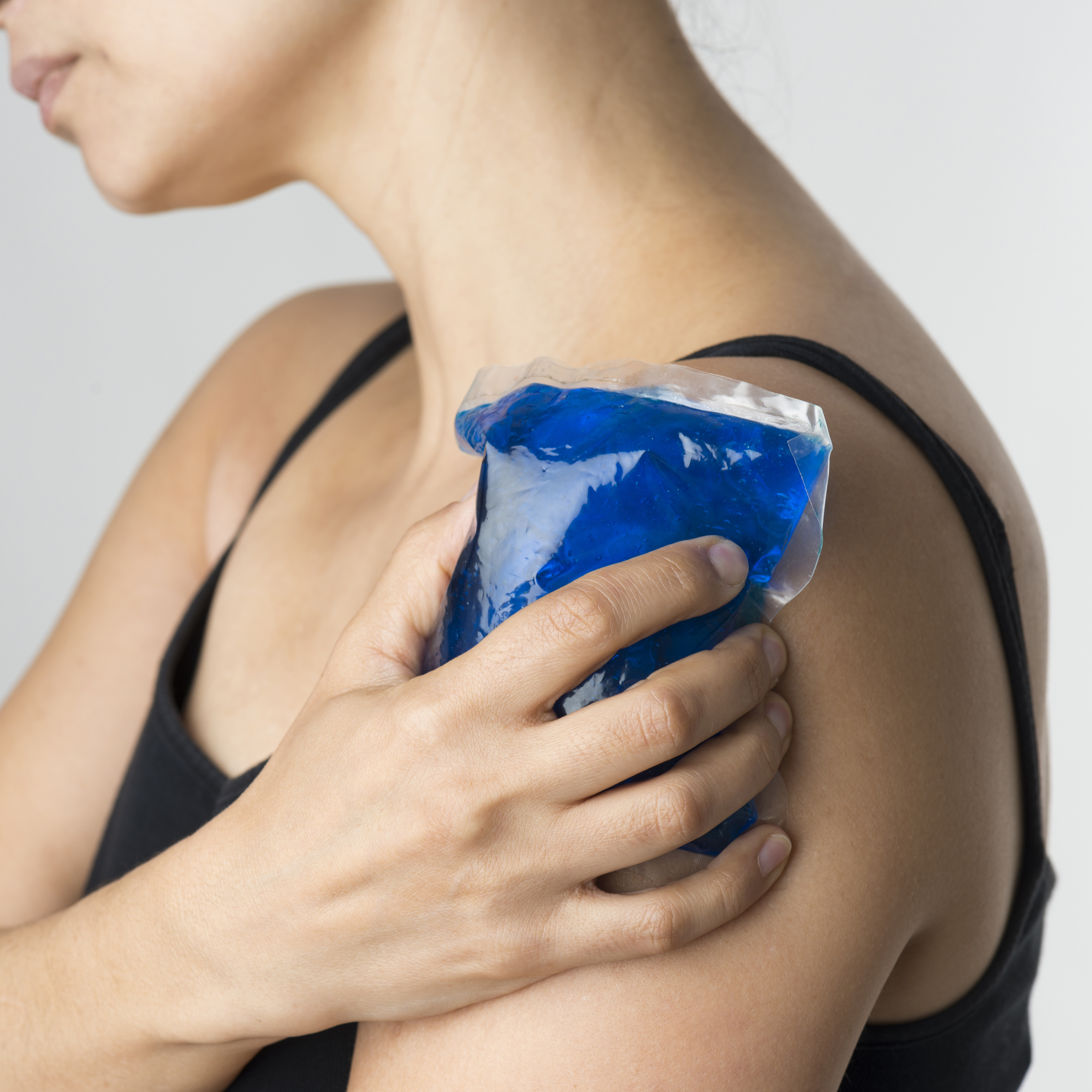 Woman cooling her shoulder/upper arm with a cold compress
