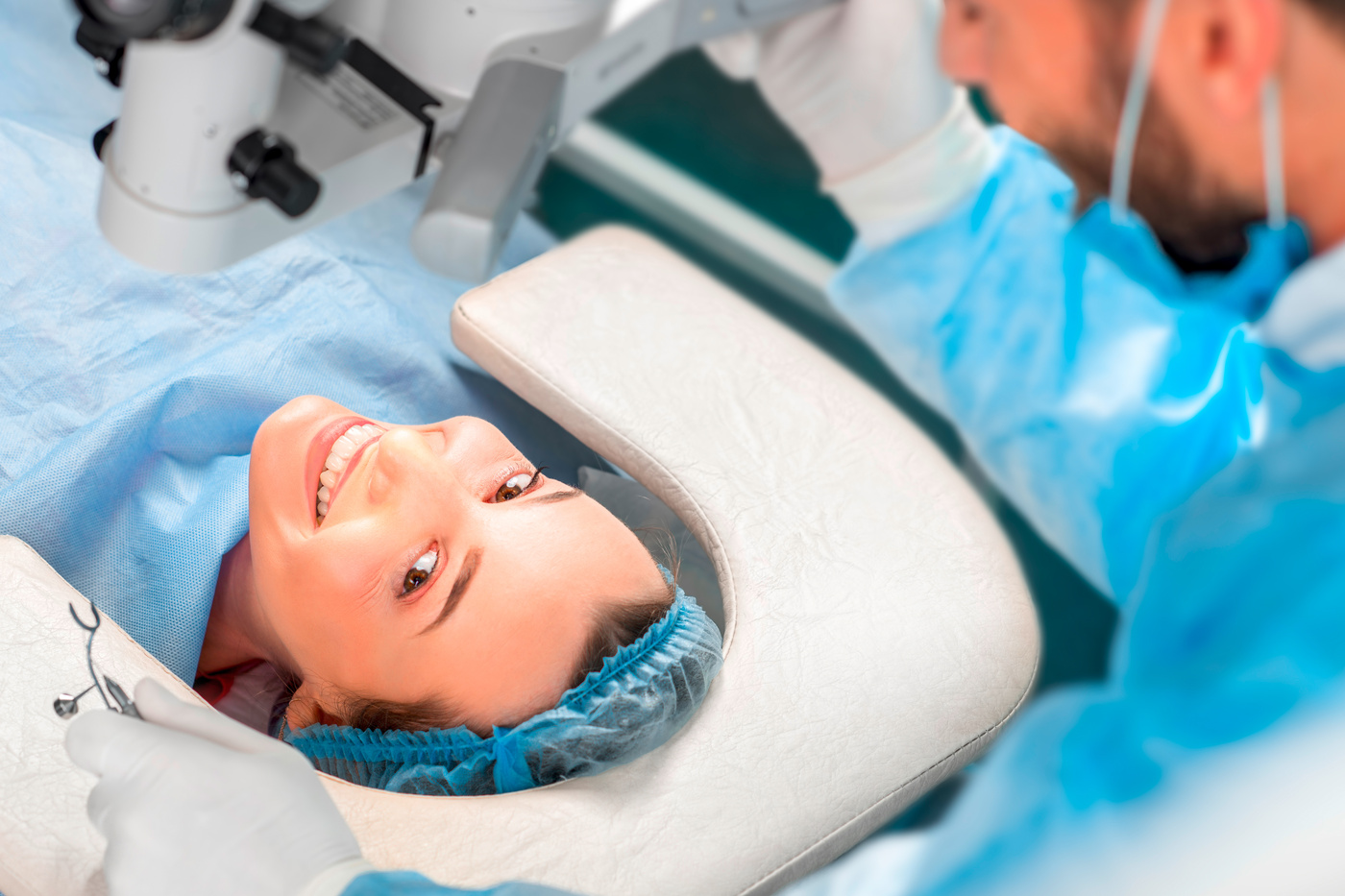 Woman lying on bed in operating theatre under light, smiling at the camera