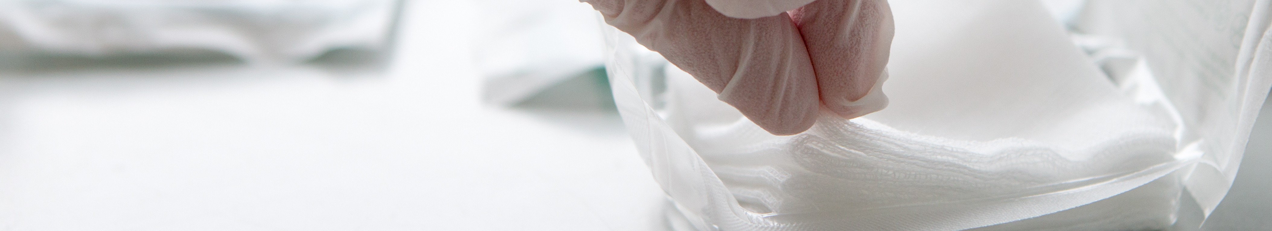 Sterile Kompresse wird mit Handschuh aus der Verpackung entnommen