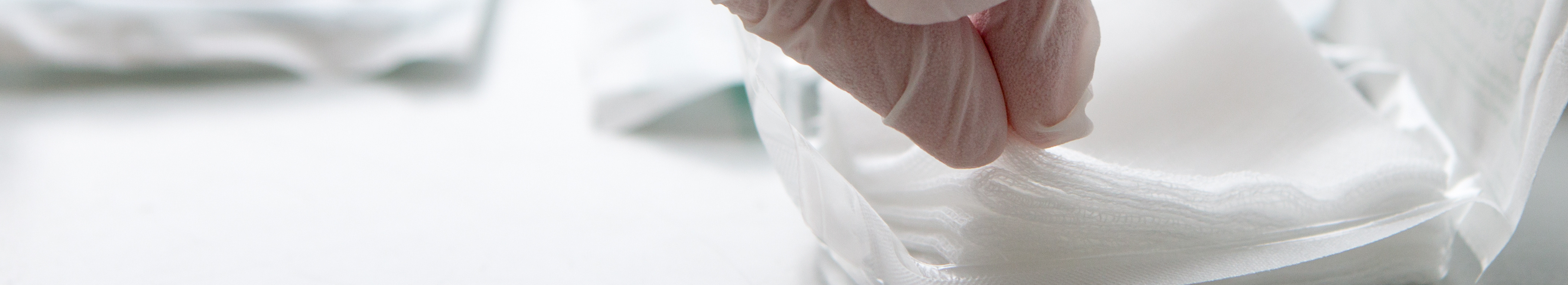 Sterile Kompresse wird mit Handschuh aus der Verpackung entnommen