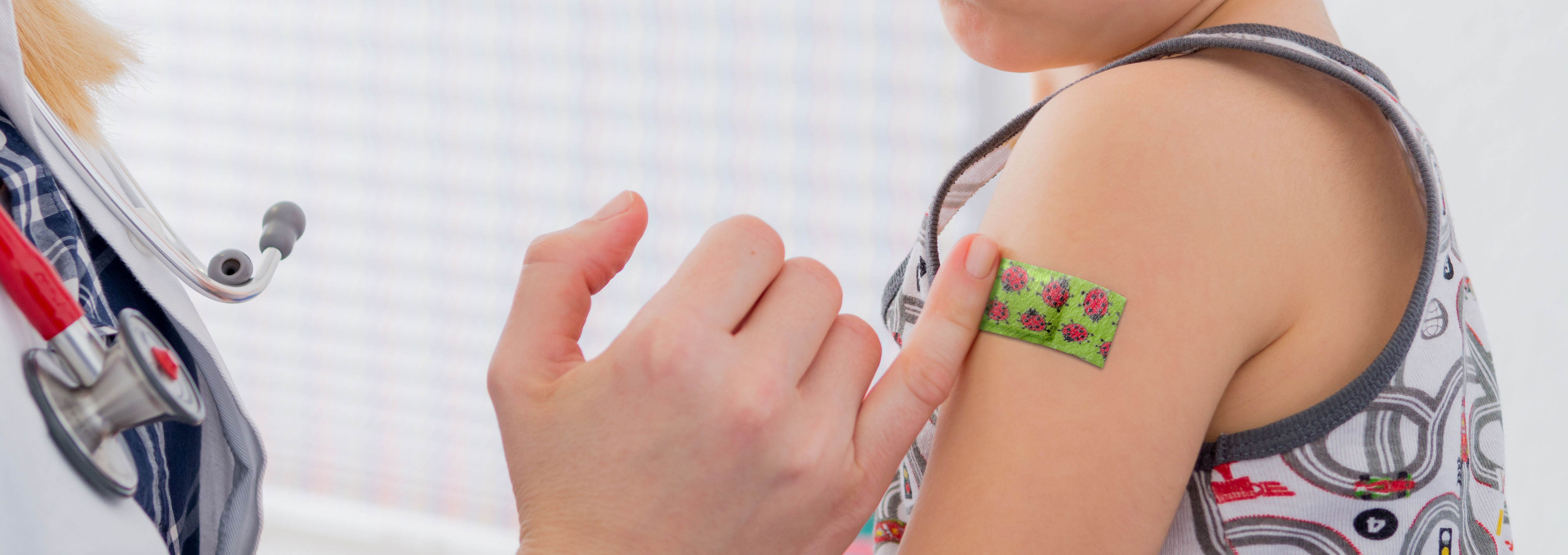 Junge bekommt das injection color Injektionspflaster mit dem Motiv Marienkäfer auf den Arm geklebt