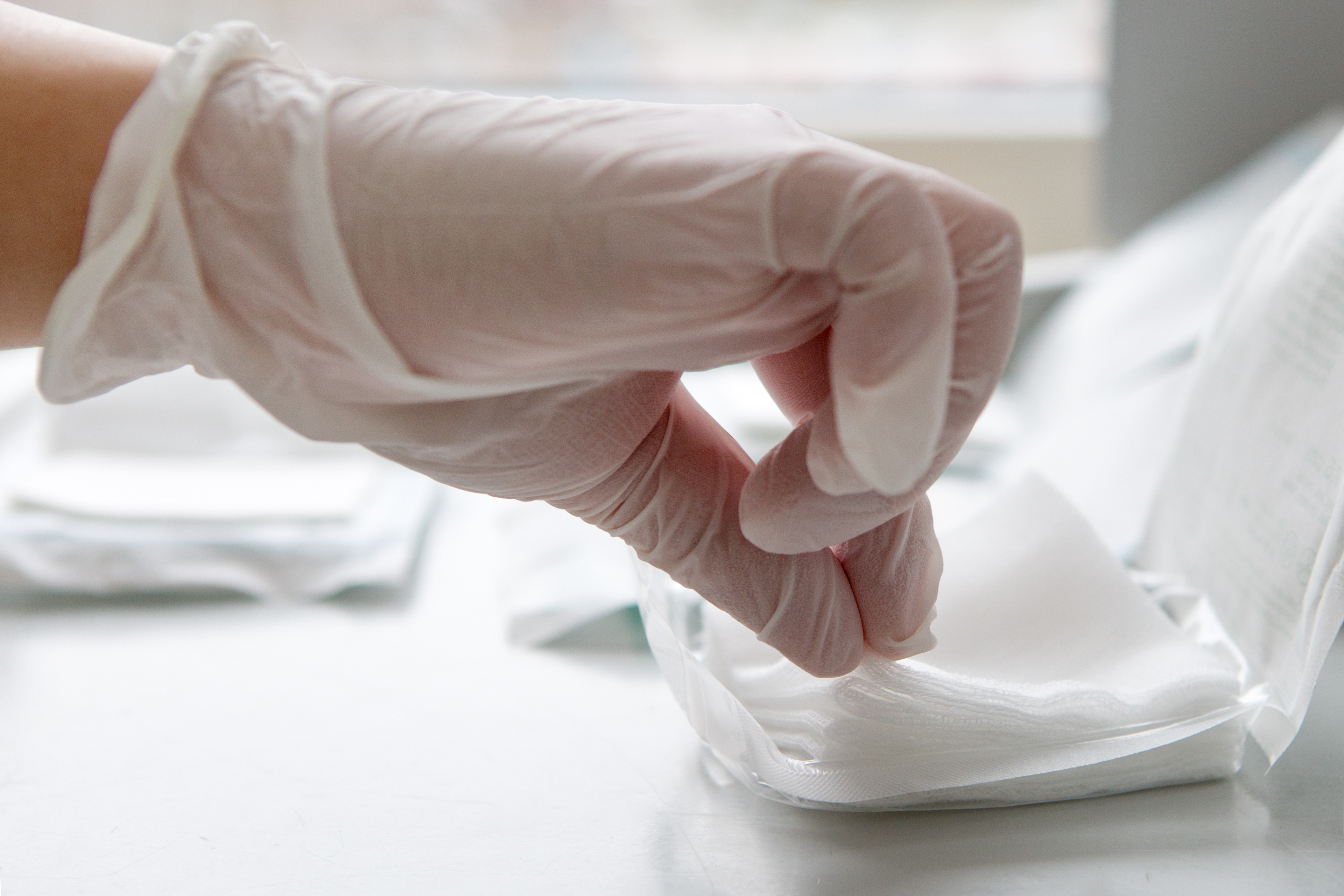 Sterile swabs being removed from packaging with gloves